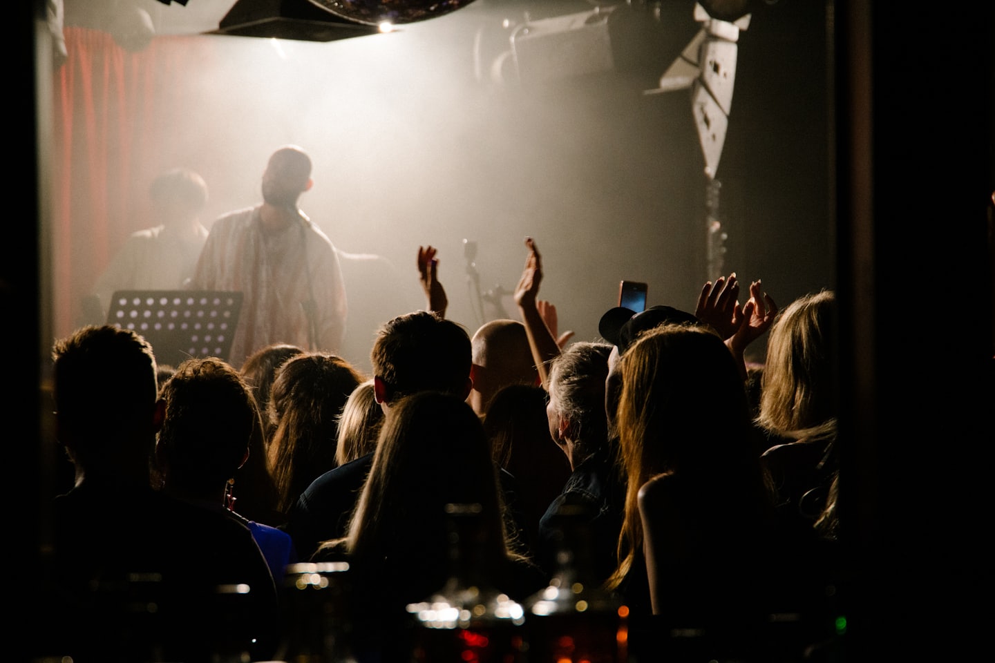 Concert audience members reach toward a performer on stage.